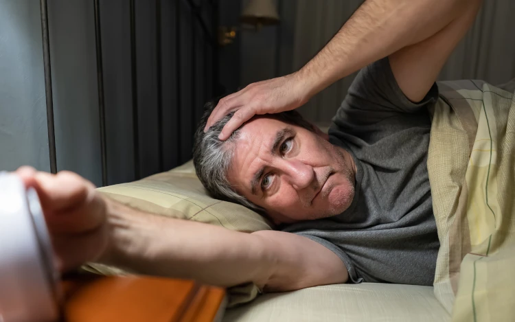 Schlafloser Mann schaut auf Wecker